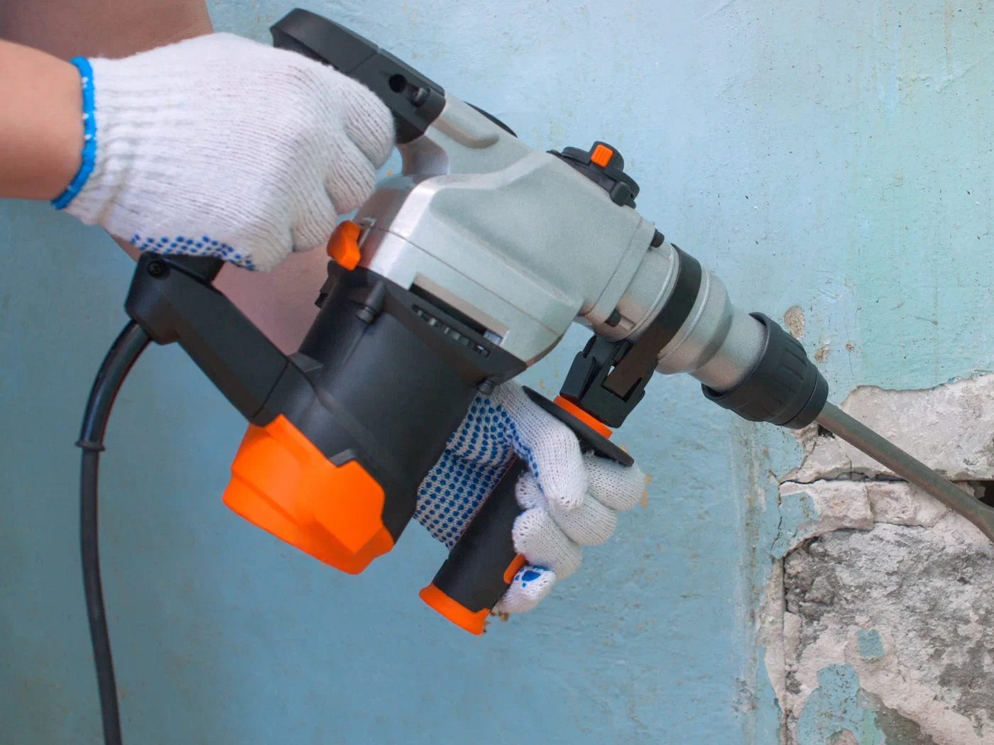 A gloved installer punching a rotary hammer drill into a plaster wall, the kind of installation Lightwave APX is designed to avoid.
