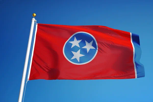 State flag of Tennessee flying against a blue sky.