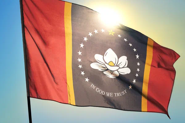 State flag of Mississippi flying against a sunlit sky.